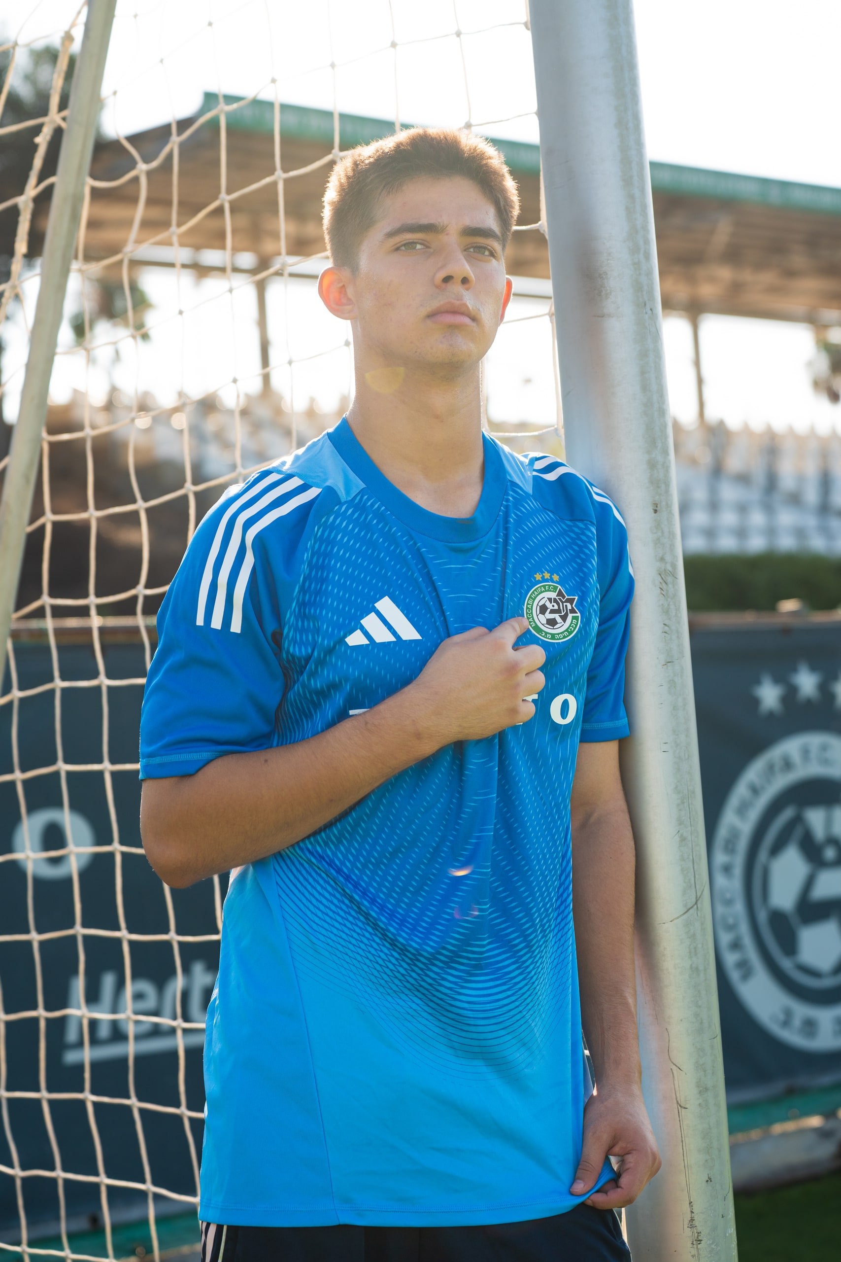 Player in blue kit leaning on the goalpost
